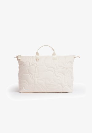 Kremfarvet quiltet shopper taske med korte håndtag og lynlåslukning, vist mod en hvid baggrund.
