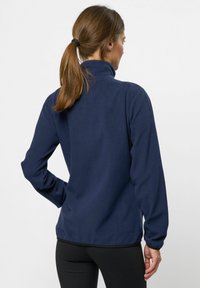 Marinblå fleecejacka med hög krage, långa ärmar och elastiska muddar. Mjuk textur, avslappnad passform, och inga synliga detaljer eller mönster.