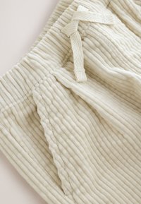Shorts en velours côtelé crème avec une texture côtelée verticale, dotés d'une taille à cordon et de poches latérales.
