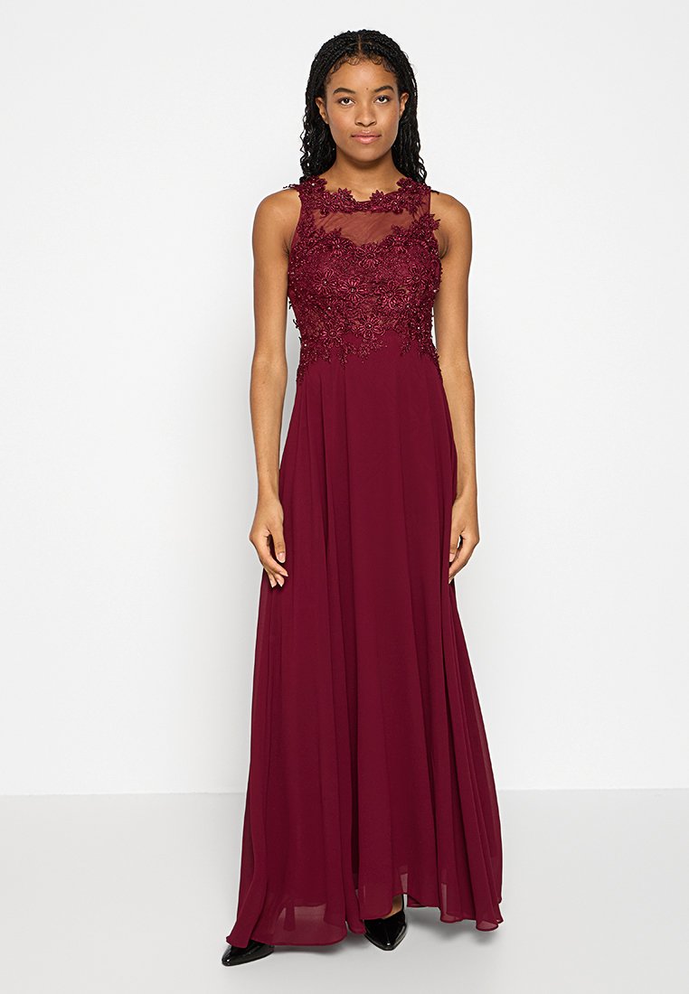 Bordowa sukienka z dopasowaną koronkową górą, zdobioną haftem kwiatowym, oraz zwiewnym dołem. Bez rękawów, z przezroczystym detalem przy dekolcie.