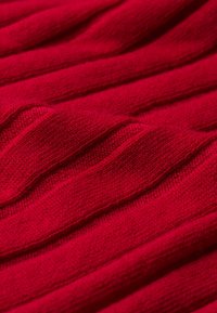 Tissu tricoté rouge à côtes avec une surface douce et texturée et des détails de couture visibles.