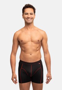 Schwarze Boxershorts mit glatter Textur, ausgestattet mit roten Akzenten und einem geprägten Bundesbund, auf dem "DANISH ENDURANCE" steht.