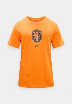 Narancssárga rövid ujjú póló a KNVB oroszlántalpával és fekete Nike swoosh logóval a mellkas közepén, sima háttér előtt.