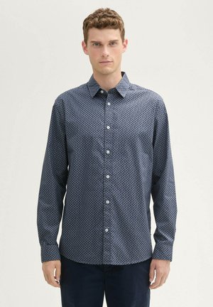 Dunkelblaues Hemd mit Knöpfen, das ein Muster mit kleinen geometrischen Formen zeigt, lange Ärmel und einen klassischen Kragen hat. Bequeme Stofftextur.