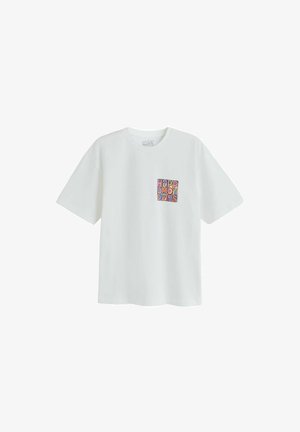 White short-sleeve T-shirt with colorful block text "HAPPY MONDAYS" on left chest.