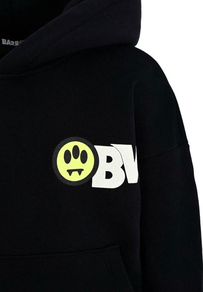 Felpa nera con cappuccio caratterizzata da un grande logo bianco "OBV" e una grafica rotonda gialla con un volto e zanne nella parte anteriore. Tessuto morbido.