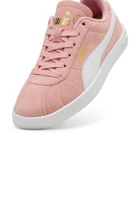 Baskets en daim rose avec une bande latérale blanche et un logo doré. Elles présentent un bout arrondi, un design à lacets et une semelle blanche texturée.