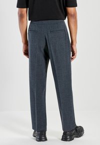 Mørkegrå skræddersyede bukser med en tekstureret finish, to baglommer og et design med lige ben, kombineret med sorte atletiske sko.