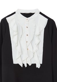 Schwarze Bluse mit einem weißen Rüscheneinsatz, mit goldenen Knöpfen und hohem Kragen. Der Stoff wirkt glatt, mit einem kontrastierenden Texturunterschied zwischen den Farben.