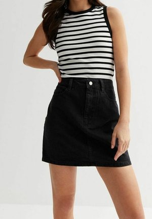 Un haut sans manches noir et blanc à rayures associé à une jupe en denim noire taille haute ; comporte une fermeture à boutons et un design classique à cinq poches.