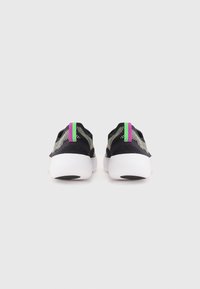 Sorte mesh sneakers med en struktureret overflade, med lilla hæl accenter og en hvid sål med sorte detaljer. Enkel, lav-top design.