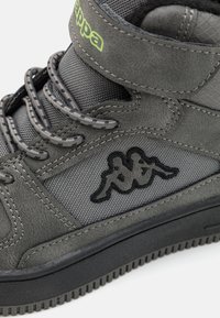 Grå höga sneakers med en texturerad ovandel, central snörning, ett kardborreband och svart logodetalj. Gummisula med räfflad mönstring.