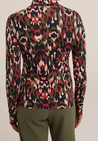 Dlouhý rukáv top vyrobený z pružné tkaniny, zdobený barevným abstraktním vzorem v zelených, červených, růžových a námořnických odstínech. Vysoký límec.