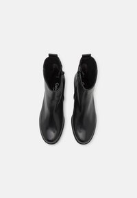 Botas de cuero negras hasta el tobillo con un diseño elegante, que cuentan con una cremallera lateral, punta redondeada y un acabado suave. Forro interior suave visible.