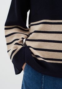 Pulover tricotat cu dungi orizontale de culoare bleumarin închis și bej. Fit lejer, cu manșete și tiv ribate, material din amestec de bumbac, suprafață texturată.