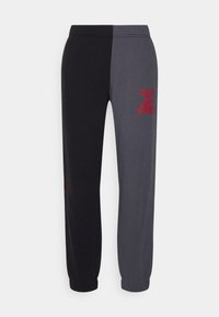 Pantalones de chándal en dos tonos, negro y gris oscuro, con puños elásticos y el logo rojo de Quiksilver en el muslo derecho.