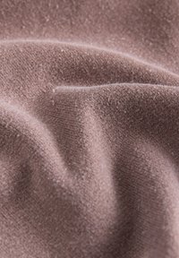 Tessuto morbido e texture in un colore malva, caratterizzato da una superficie liscia e leggermente pelosa, con leggere scanalature e variazioni di tonalità.