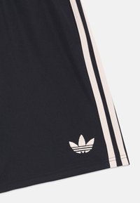 Črne športne kratke hlače z belimi stranskimi črtami, izdelane iz gladkega materiala. Imajo majhen bel Adidas logotip blizu roba.
