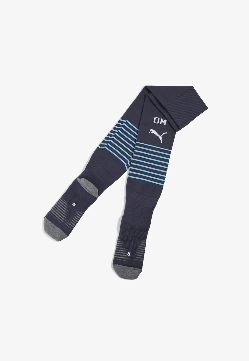 Granatowe skarpetki sportowe z poziomymi jasnoniebieskimi paskami, z logo Puma i napisem "OM". Zawierają wzmocnione szare pięty i palce.