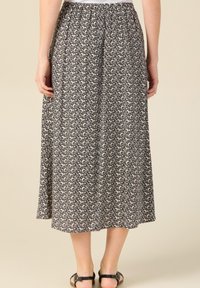 Falda midi de estampado en blanco y negro con cintura elástica, tela suave y diseño fluido. Presenta un sutil estampado floral.