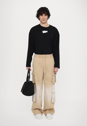 Zwarte langekouch mouw shirt; beige cargobroek met zakken; witte sneakers; houdt een zwarte tas vast. Minimalistisch ontwerp, zachte texturen.