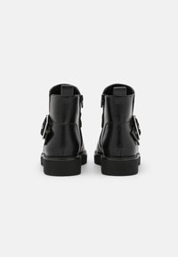 Černé kožené kotníkové boty s hladkým povrchem, s uzavíráním na zadním zipu a plochou gumovou podrážkou. Má odnímatelný dekorativní prvek na boku.