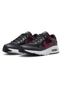 Baskets noires et rouges Nike en matériaux mesh et cuir, avec un design de swoosh bien en évidence, une semelle intermédiaire blanche et une semelle extérieure en caoutchouc texturé.