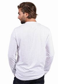 Long-sleeve white t-shirt with a crew neck, made of soft cotton. Features a smooth texture, casual fit, and straight hemline.