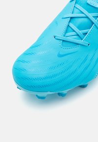Chaussure de football turquoise avec une tige texturée, présentant une finition lisse et des contours courbés. Inclut des lacets et des crampons assortis.