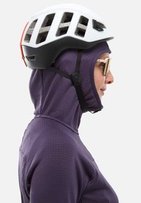 Personne portant une veste à capuche violette, un casque de vélo ventilé blanc et noir, et des lunettes de soleil réfléchissantes, tourné vers la droite sur un fond blanc.