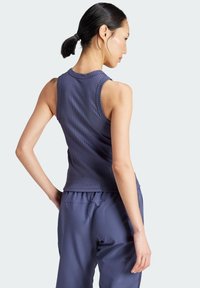Marineblauwe geribbelde tanktop met een aansluitend ontwerp, brede schouderbanden en een gebogen zoom. Draagt met bijpassende broek; gladde textuur.
