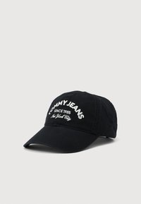Svart baseball cap med buet brem som har hvit brodert tekst "TOMMY JEANS SINCE 1985 New York City" på frontpanelet.
