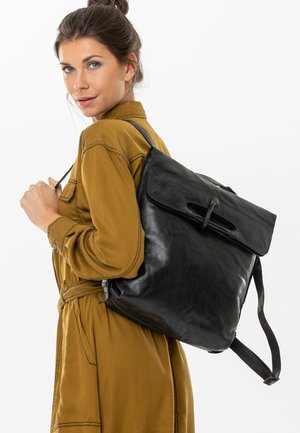 Zaino in pelle nera con chiusura a roll-top e spallacci regolabili, caratterizzato da una texture liscia e un design elegante. Accentuato da un gancio sicuro.