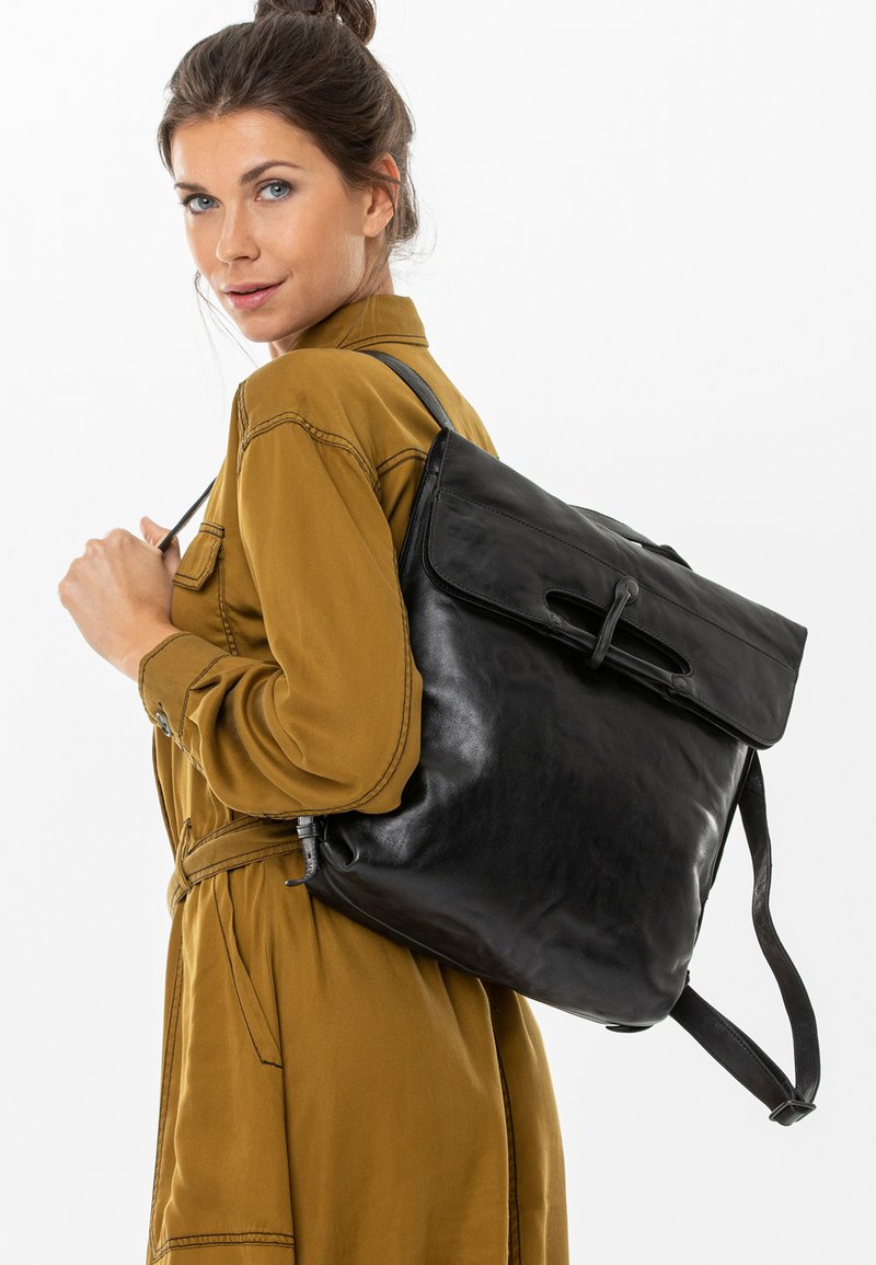 Zaino in pelle nera con chiusura a roll-top e spallacci regolabili, caratterizzato da una texture liscia e un design elegante. Accentuato da un gancio sicuro.