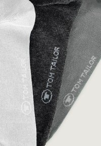 Tres pares de calcetines: uno blanco, uno gris oscuro y uno gris medio. Cada uno cuenta con una textura suave y un logo impreso cerca del puño.