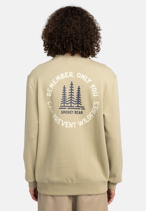 Beige sweatshirt featuring a circular graphic on the back with trees and the text "REMEMBER, ONLY YOU CAN PREVENT WILDFIRES." Soft texture.