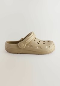 Beige Kunststoffclogs mit Luftlöchern, Riemen, strukturiertem Profil und erhöhten Akzenten an den Seiten. Rund geformte Zehenpartie für Komfort.