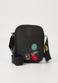 Borsa a tracolla nera in tessuto con tracolla regolabile, caratterizzata da colorati patch ricamati di ciliegie, sole e logo in blu e rosso.