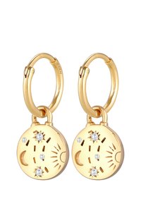 Des boucles d'oreilles en or en forme de créole avec un pendentif rond présentant des motifs en relief de soleil et de lune, agrémentés de trois pierres transparentes. Surface en métal lisse avec une finition polie.