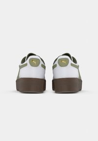 Zapatillas blancas con acentos en verde oliva y logo dorado. Suela de goma marrón gruesa y collar acolchado. La vista trasera destaca los detalles contrastantes en la parte superior.