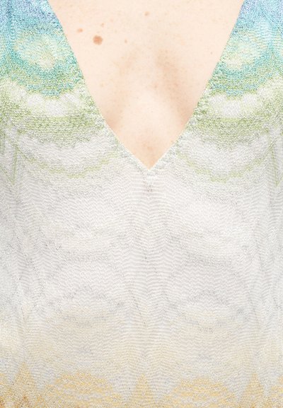 Κοντινό πλάνο στην περιοχή του στήθους που φοράει ένα ελαφρύ πλεκτό τοπ με βαθύ V-λαιμό και παστέλ κυμματιστά σχέδια σε αποχρώσεις του μπλε, πράσινου και κίτρινου.