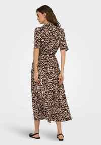 Robe maxi en imprimé léopard avec des manches courtes, design enroulé et taille cintrée ; possède un tissu doux et léger et une silhouette fluide.