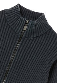 Suéter de cremallera en ripstop gris oscuro con un alto cuello y detalle de cremallera metálica, que presenta un patrón de punto texturizado en todo el tejido.