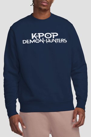 Mann trägt dunkelblauen Pullover mit weißem Text "KPOP DEMON HUNTERS" vor einfarbigem Hintergrund.