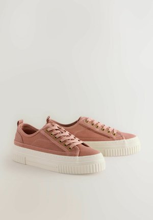 Rosa canvas-sneakers med tjock vit gummisula, rundad tå och guldfärgade öljetter. Har en sydd design och tygskosnören.