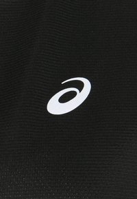 Musta urheilukangas, jossa on ribbitekstuuri ja valkoinen logo alareunassa oikealla puolella. Suunnittelu on tyylikäs ja minimalistinen.