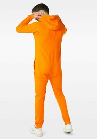 Kapitánová oranžová overal s kapucí a přiléhavým střihem, dlouhými rukávy a bočními kapsami, vyrobený z hladké, elastické tkaniny.