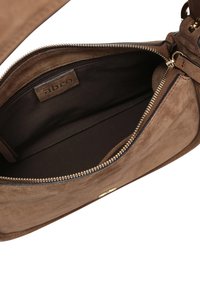 Brown suede handbag interior with a zip closure, featuring a fabric lining and a small label stitched on the inner wall. Gold hardware accents.