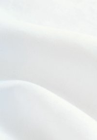 Tissu blanc lisse avec des plis doux et une texture subtile, mettant en valeur la légèreté et l'aspect aérien du matériau.