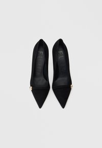 Svarte mokkasko med høye hæler og spiss tå, med en gullakcent på stroppen og preget merke på innersålen.